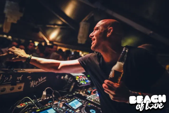 DJ legt im Abendlicht auf und prostet der Menge zu