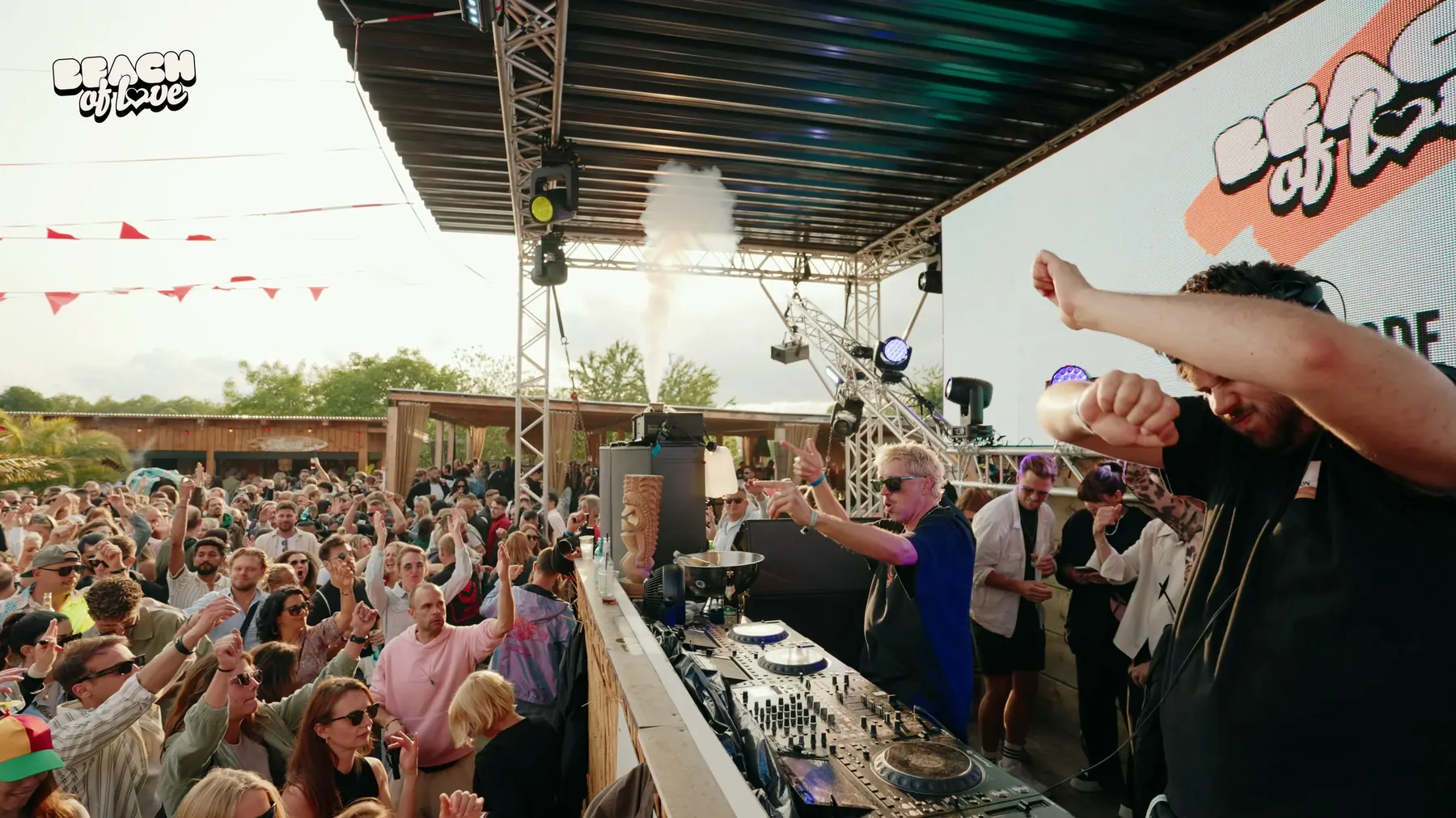 DJ feiert mit Konfetti-Kanone vor der Menge unter Wimpelketten