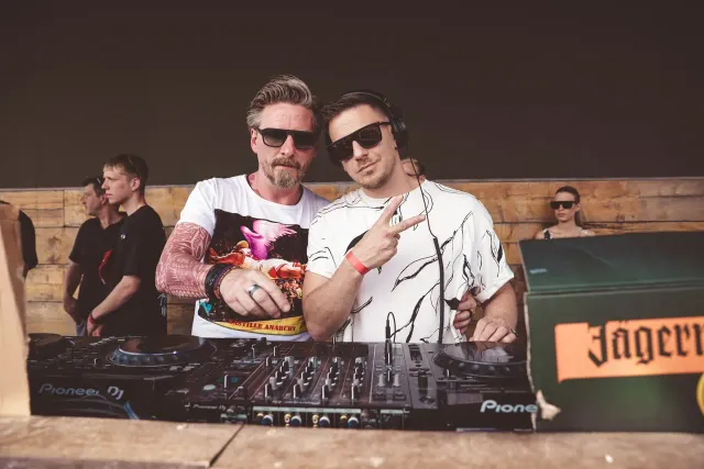 Zwei DJs posieren hinter dem Pult
