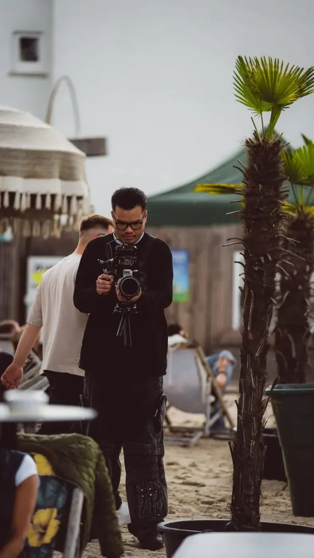 Fotograf zwischen Palmen am Strand